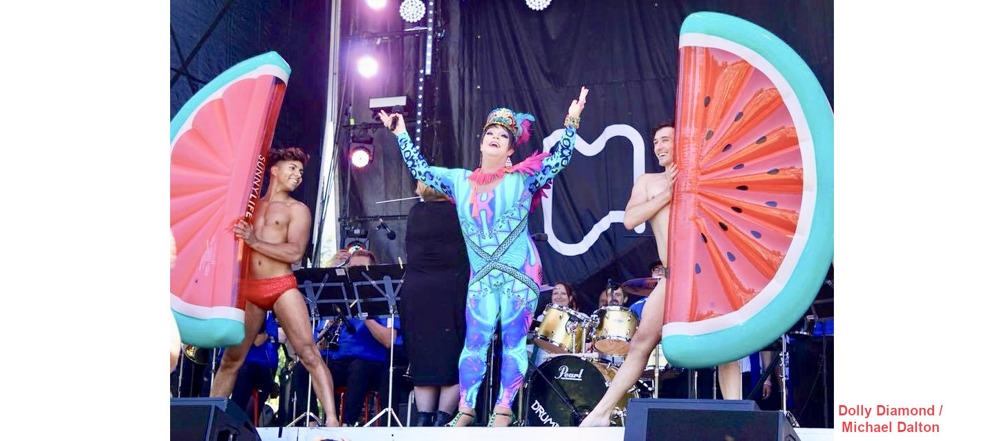 Dolly Diamond doing a fruity number - shirtless boys on the side holding large mandarin segments