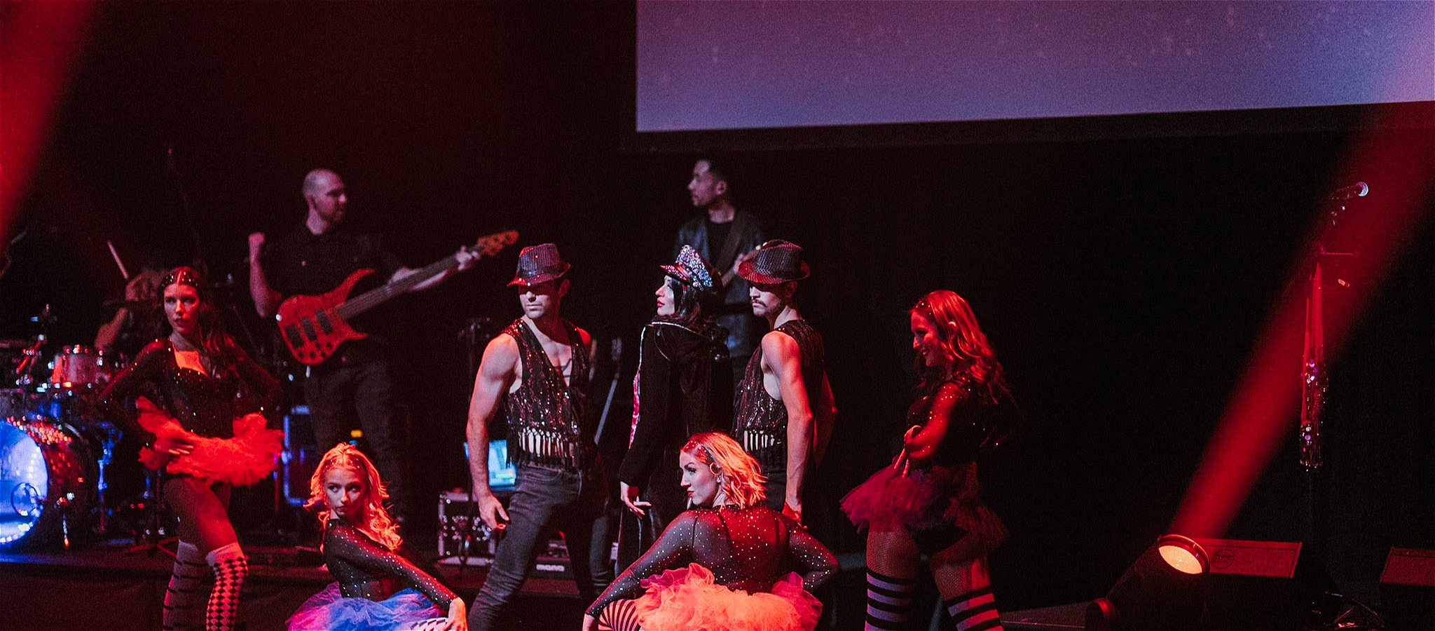 Dancers and singer on stage posing with a band in the background