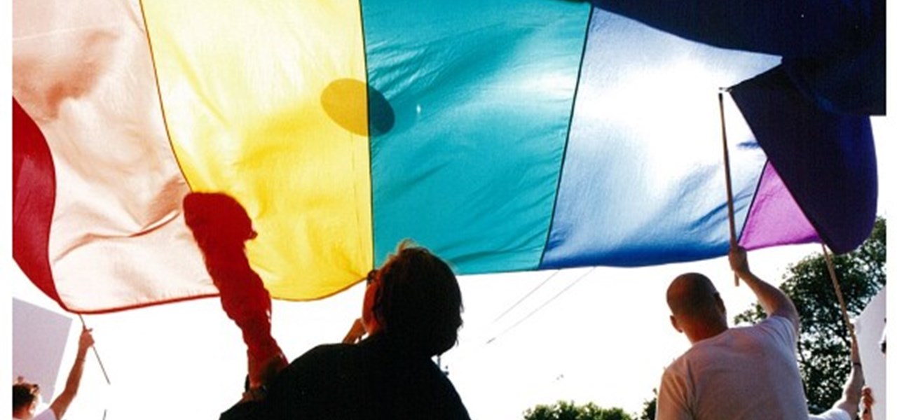 Pride March 2000 image: people holding a large rainbow banner overhead