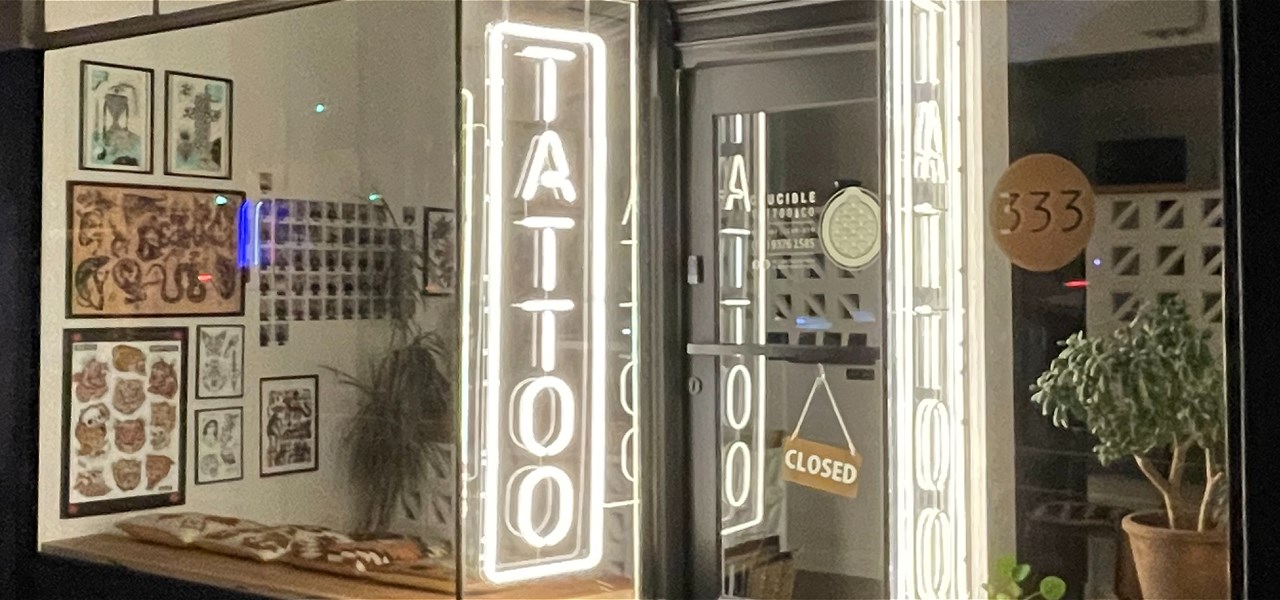Exterior photo of a tattoo studio, with bright fluorescent lights that read "Tattoo".