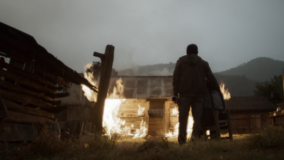Photo at dusk with a fire in the foreground and hills in the background