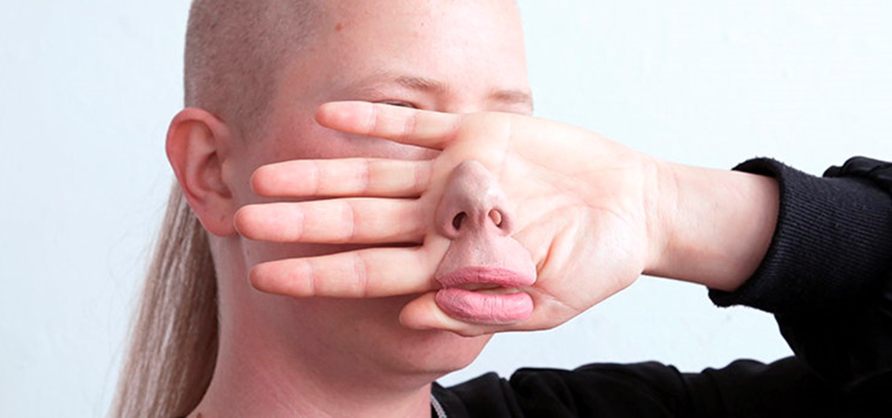 Person with their hand in front of their face, and an artificial nose in front of the hand