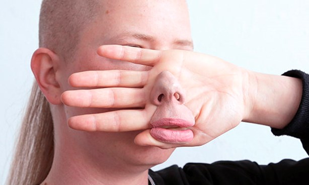 Person with their hand in front of their face, and an artificial nose in front of the hand