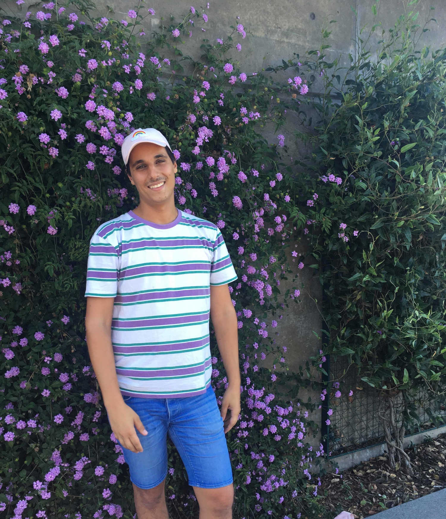 Portrait of Jason standing in front of a wall covered in flowering climbers