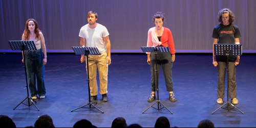 Four actors on stage with dramatic expressions on their faces