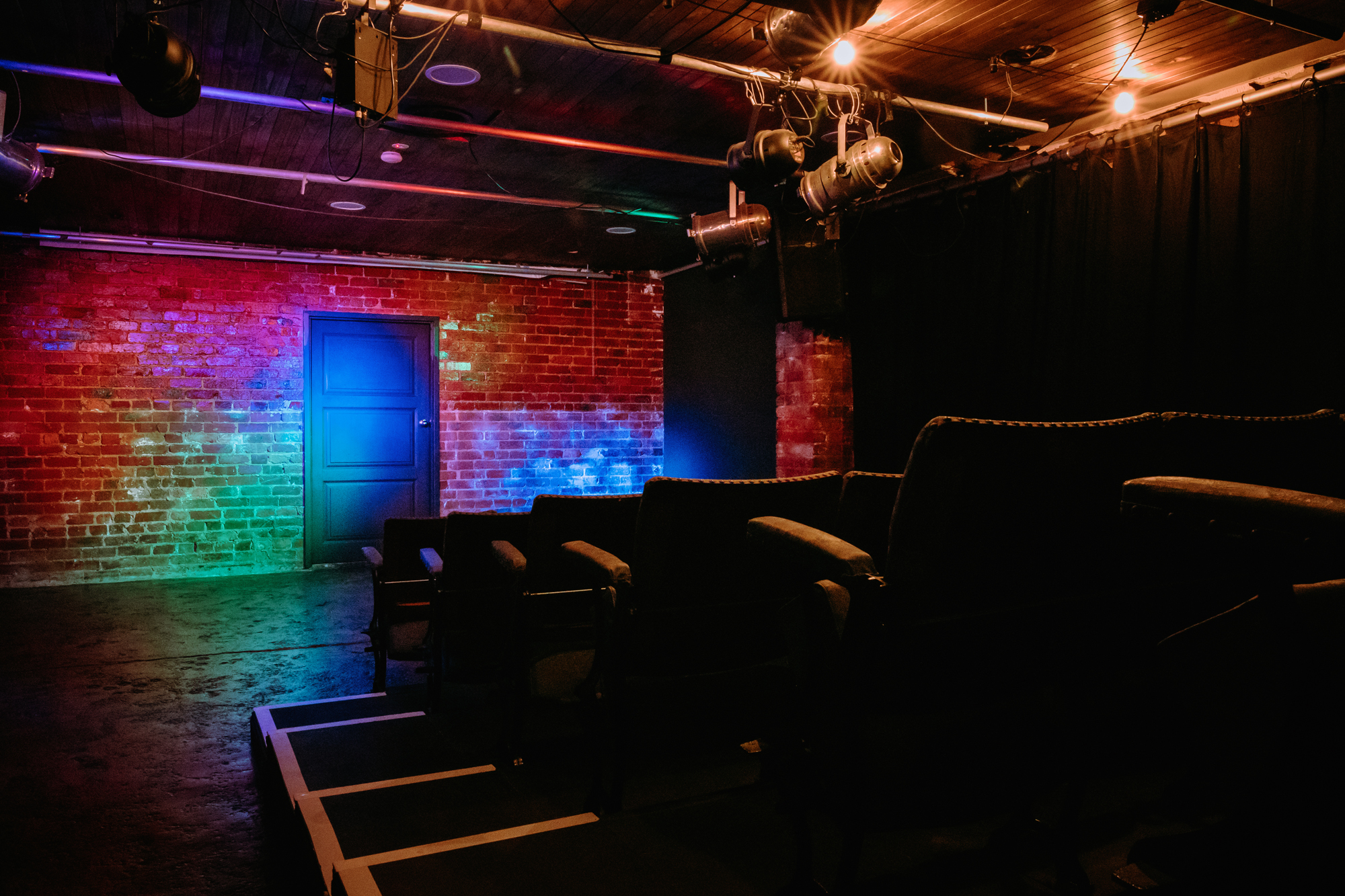 Interior of one of the Motley Bauhaus performance spaces - a sparse space with a brick wall at the rear and lighting on the ceiling
