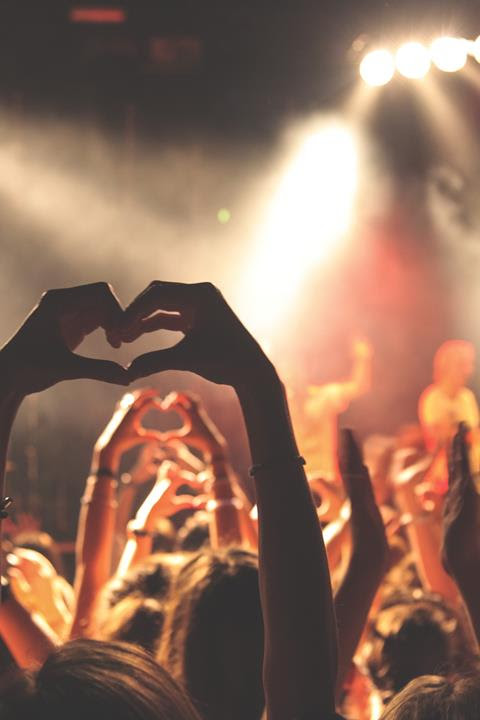 Many hands upraised, joined together to form a heart symbol