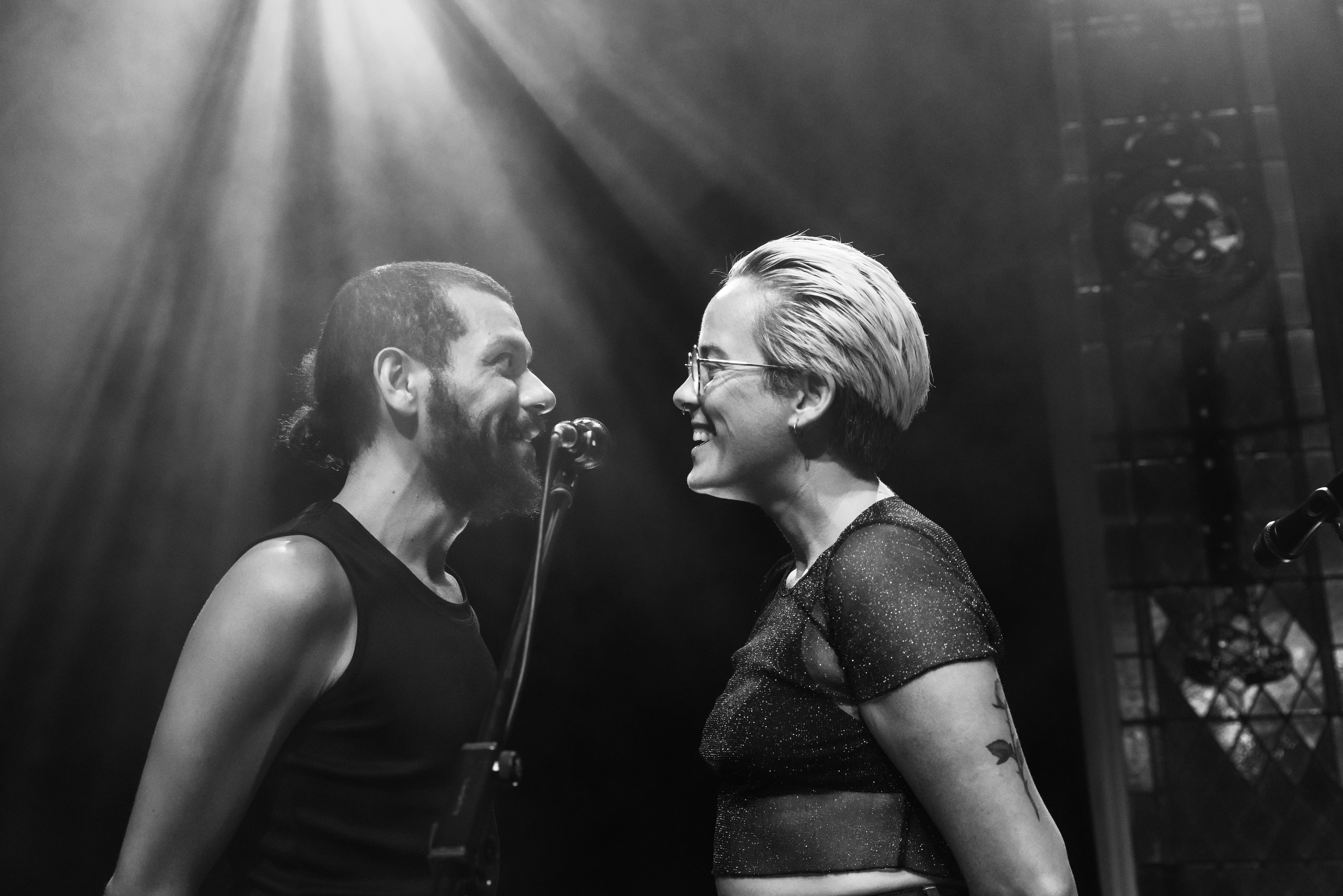 Black and white image of two people on stage, facing each other, very close to each other
