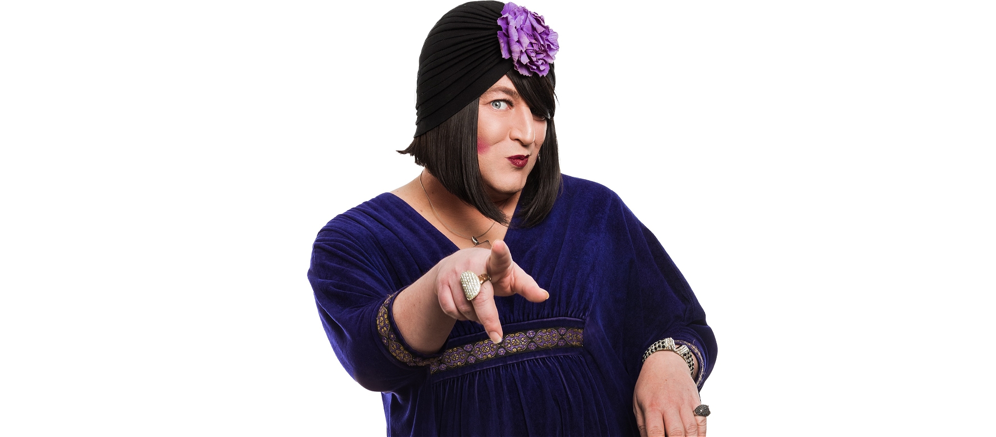 Tina Del Twist in dark blue dress looking wryly at the camera with one arm outstretched