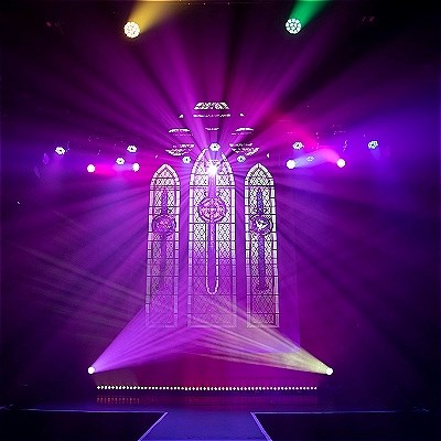 Chapel theatre with a large stained glass window and pink lighting