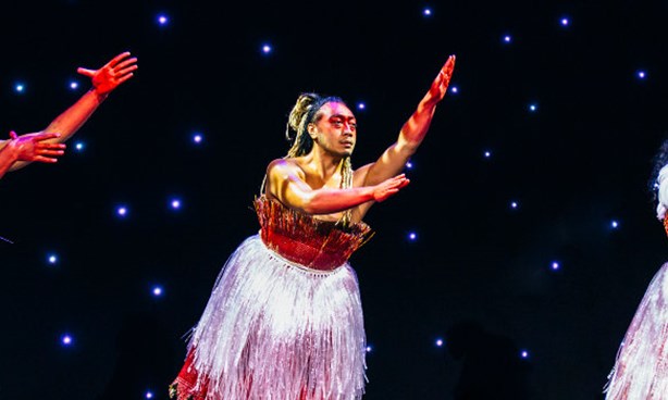 Three people of Pacific Islander appearance in dresses, arms outstretched with stars twinkling behind them