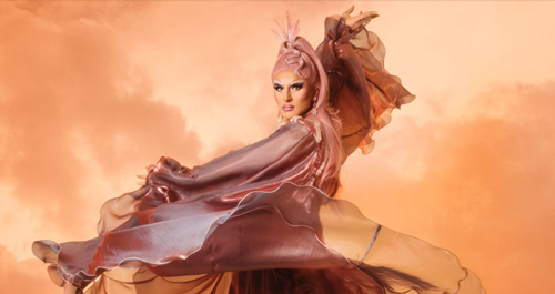 Performer wears a pink wig & flowing pink dress that is being twirled in the air around them.