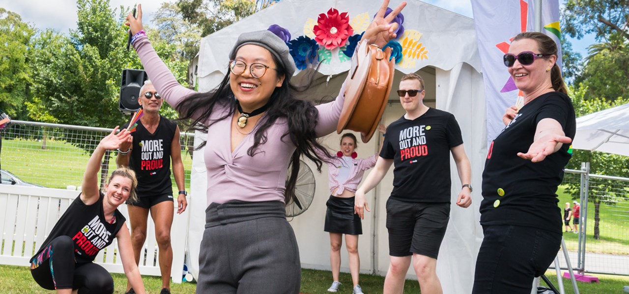 Happy people at NAB tent, Midsumma Carnival. Asian girl with hands in air on a red carpet