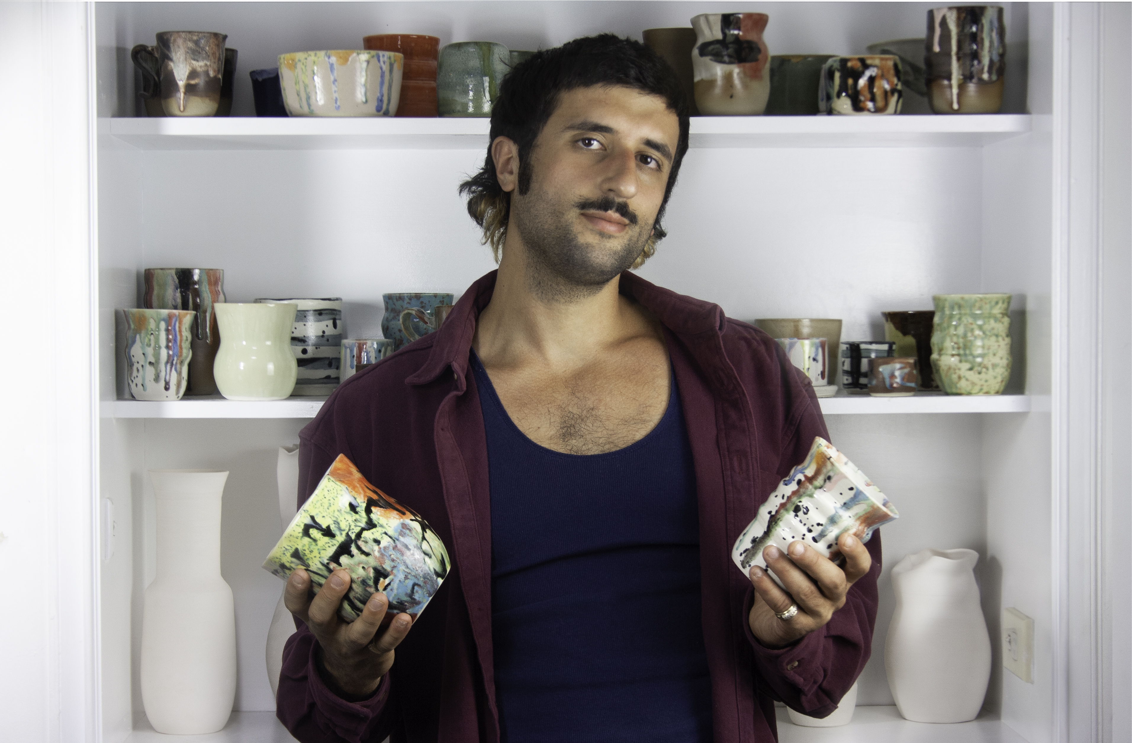 Headshot of Raphy Karanikos holding a ceramic work in each hand