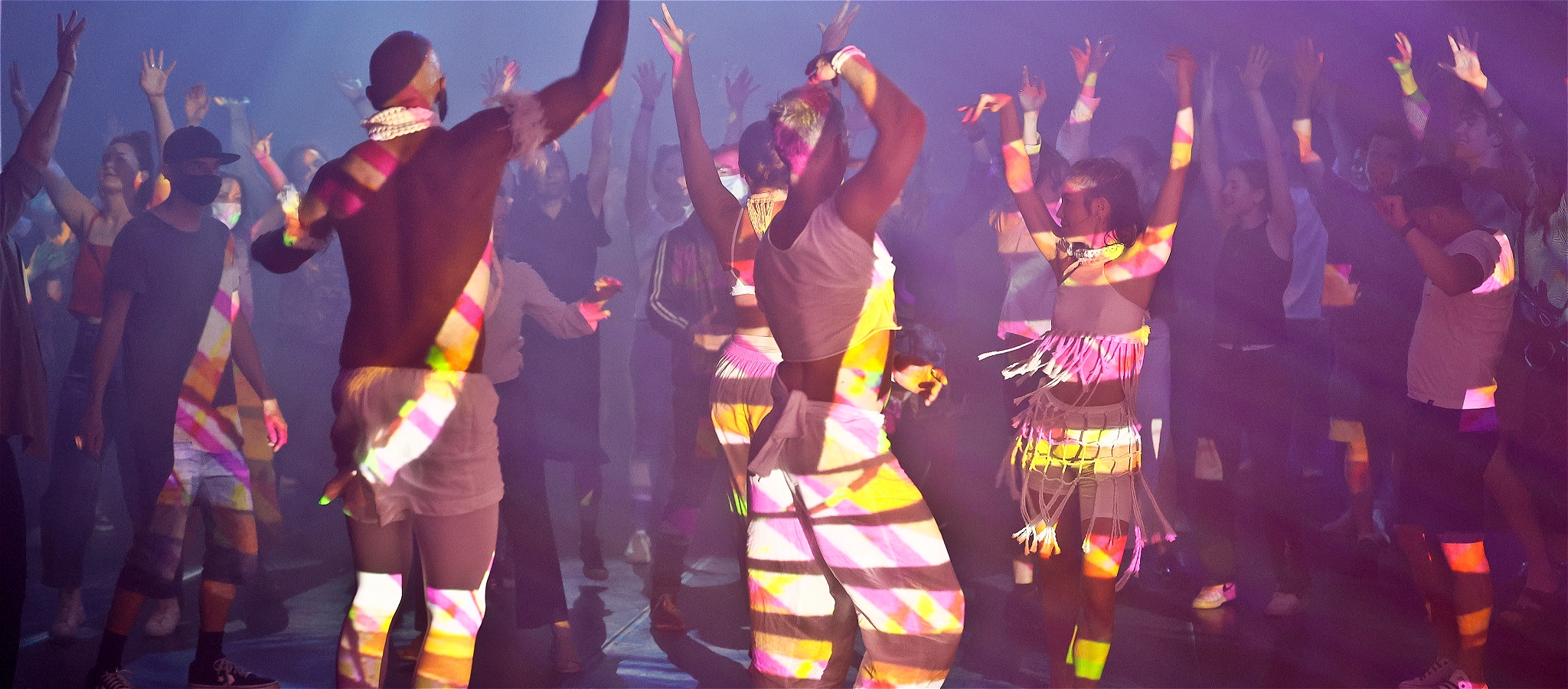 Large troupe of dancers all holding their hands in the air