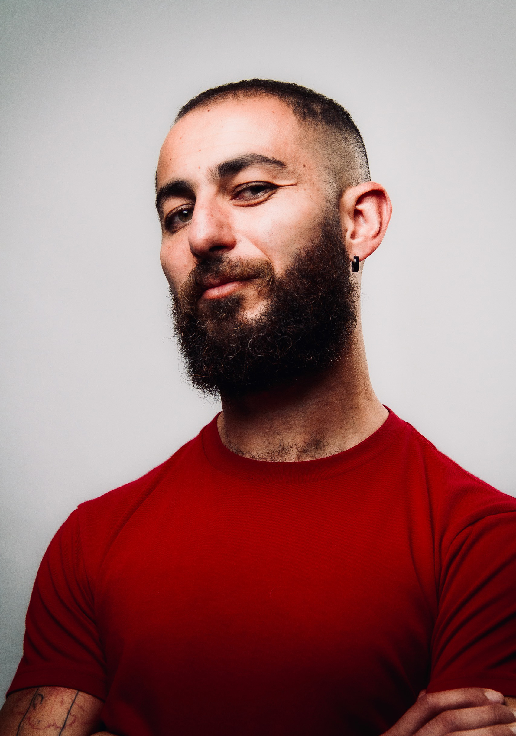 A person with a dark brown beard wearing an earring.