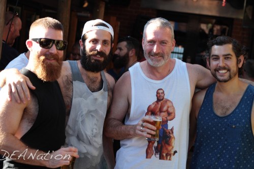 Four men in singlets huddled together and smiling for the camera