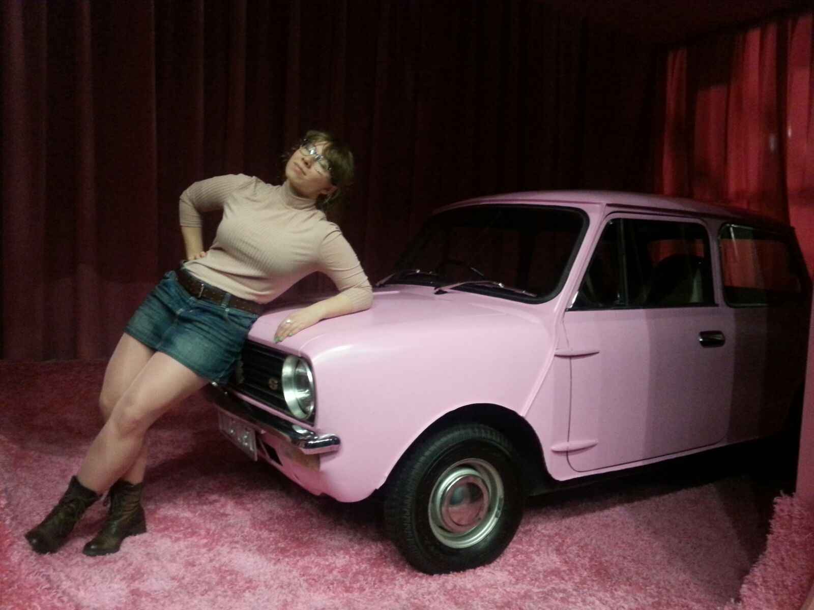 Kat Celikaite leaning on the bonnet of a pink retro car