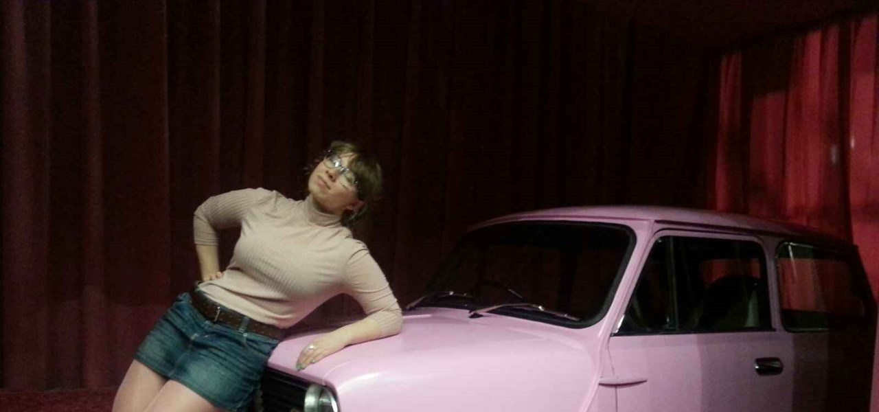 Kat Celikaite leaning on the bonnet of a pink retro car