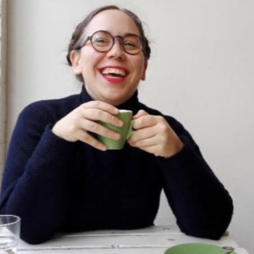 Emma Palackic holding a mug between their hands and smiling