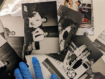 A person wearing blue gloves examines archival photographs.