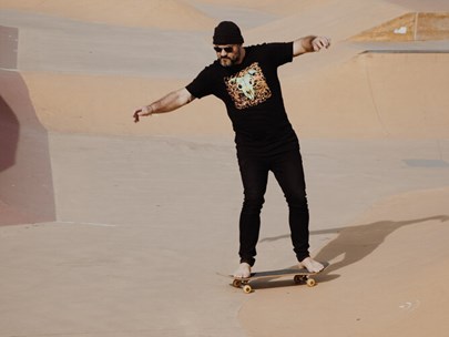 A person on a skate board wearing a Black Lamb t-shirt and black trousers