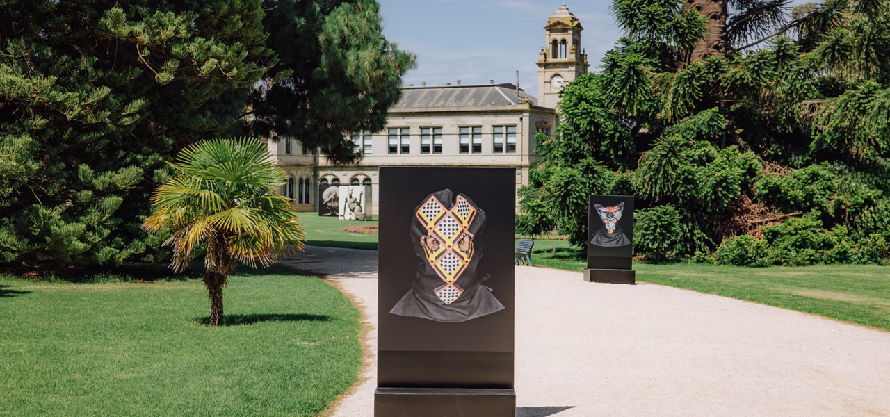 Photo of gardens of Werribee Mansion with a large black sign on the pathway