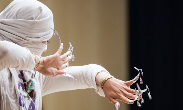 Person dressed elegantly in Indian or Middle-Eastern outfit, dancing, with very long fingernails