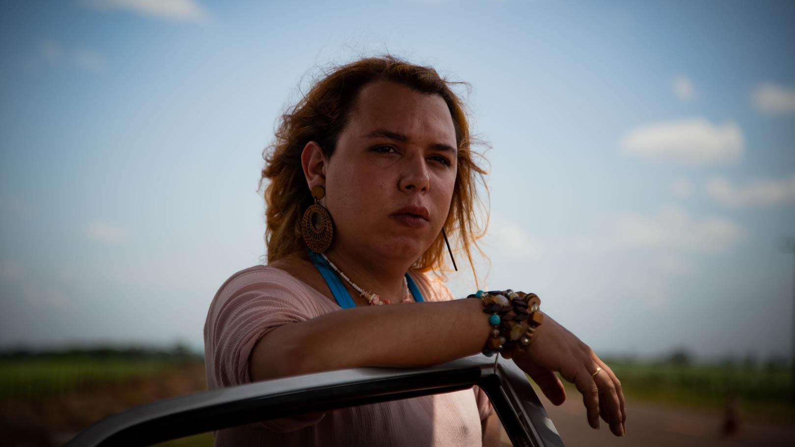 Person leaning on an open car door with a flat landscape in the background