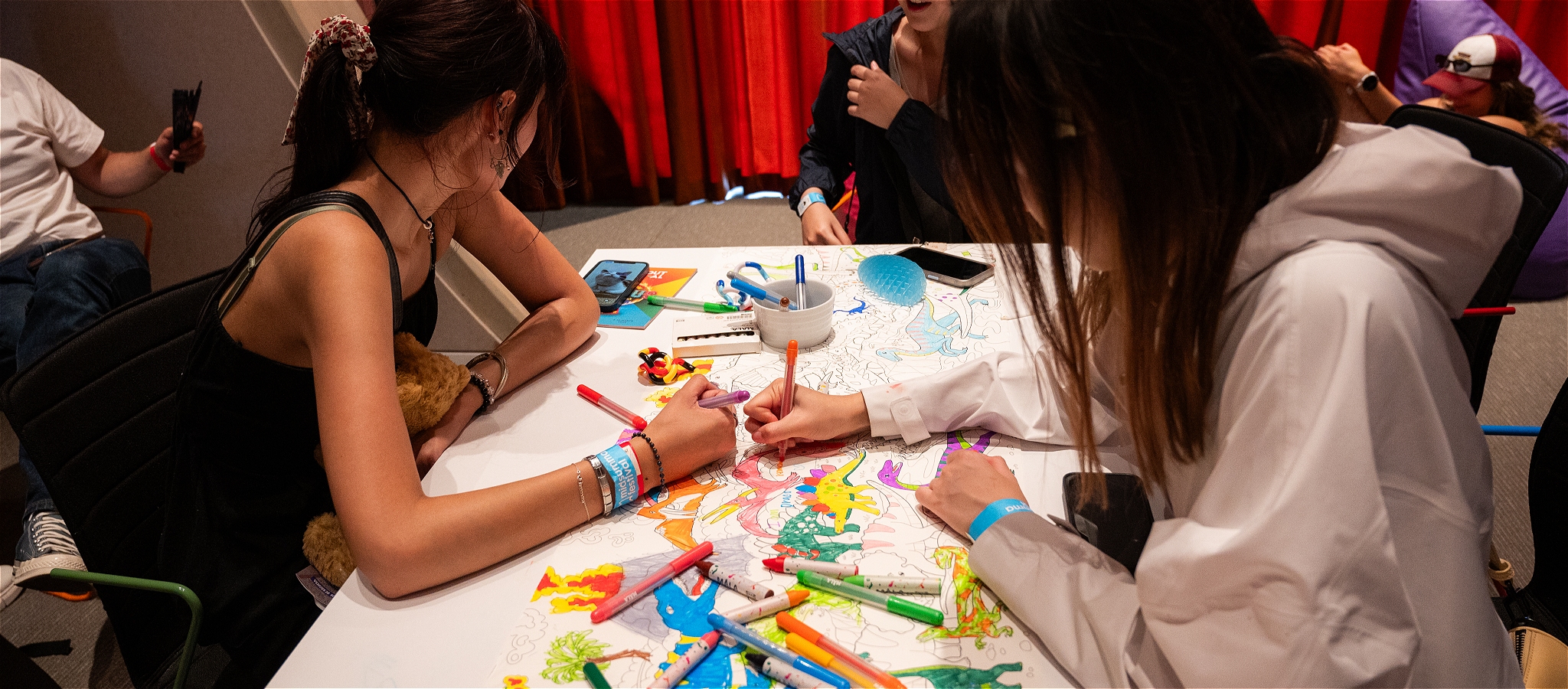 A photo of a group of people seated around a table doing some colouring in activities