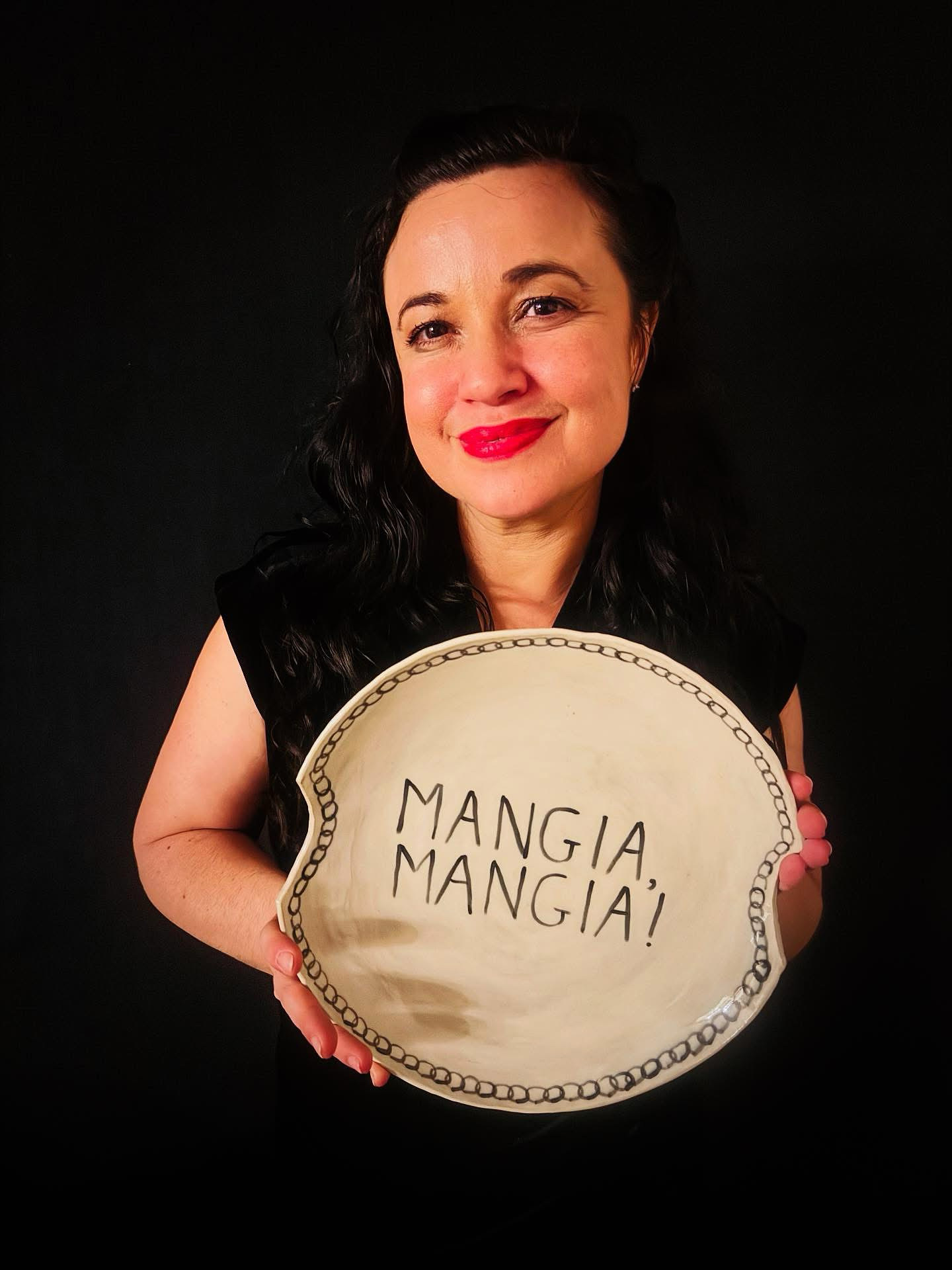 Lisa holding a plate that reads MANGIA, MANGIA!
