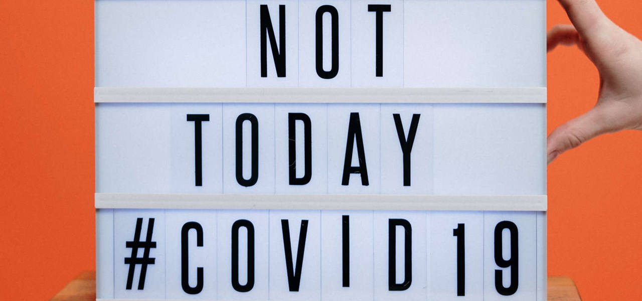 Hand holding a sign sitting on a stool that reads: 'NOT TODAY #COVID 19'