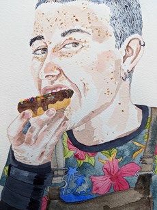 A colourfully dressed person eating a doughnut: focus on the doughnut