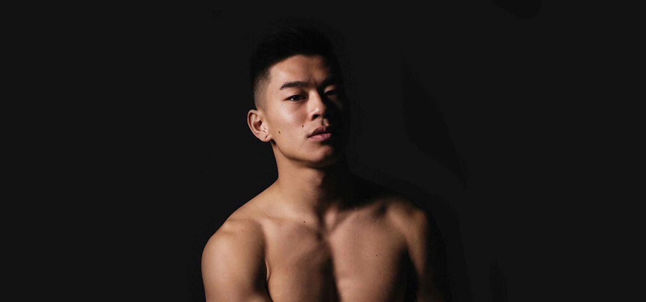 Bare-chested Asian male against a black background