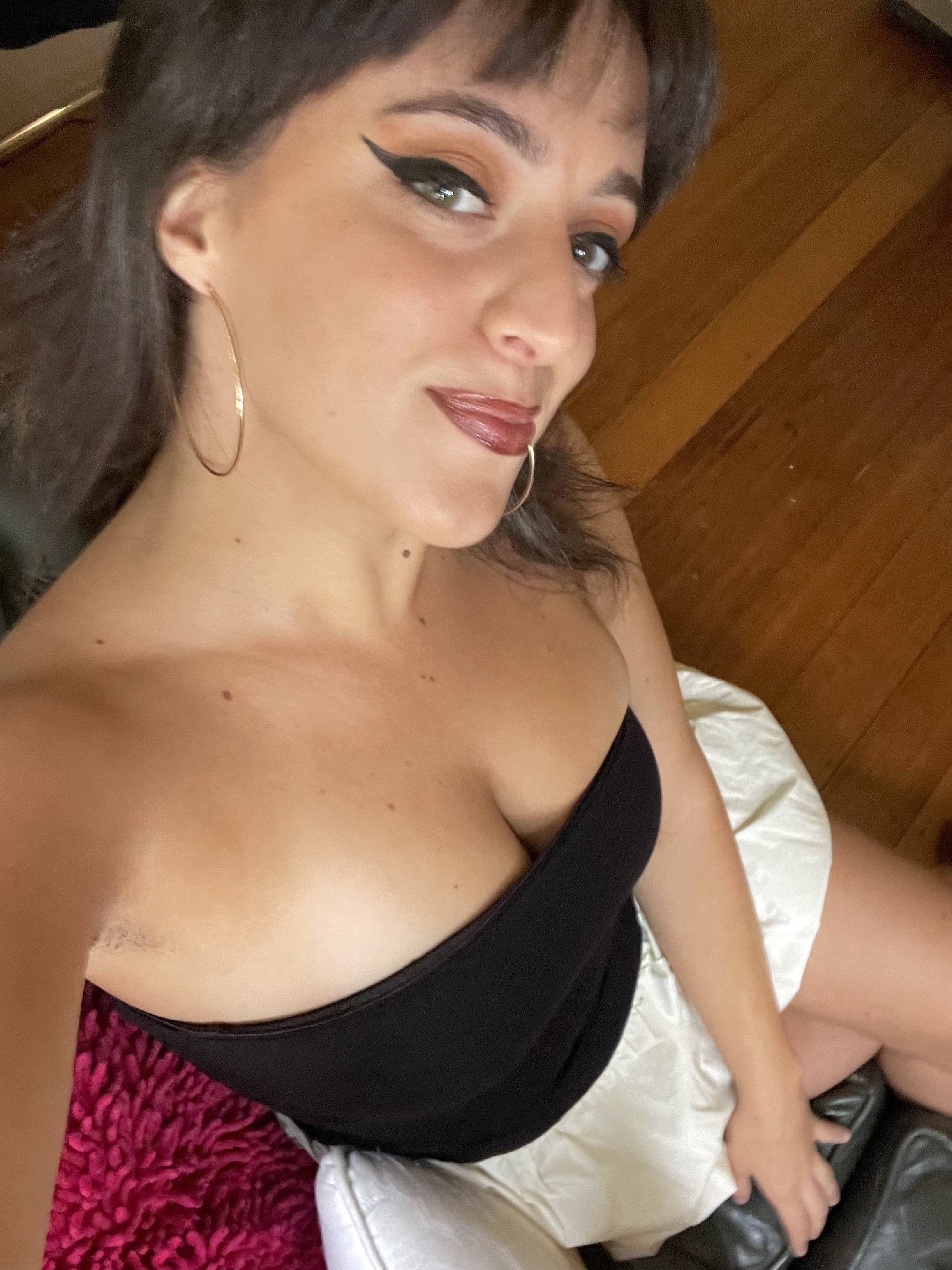 Close-up of Isadora sitting on a chair wearing a strapless top
