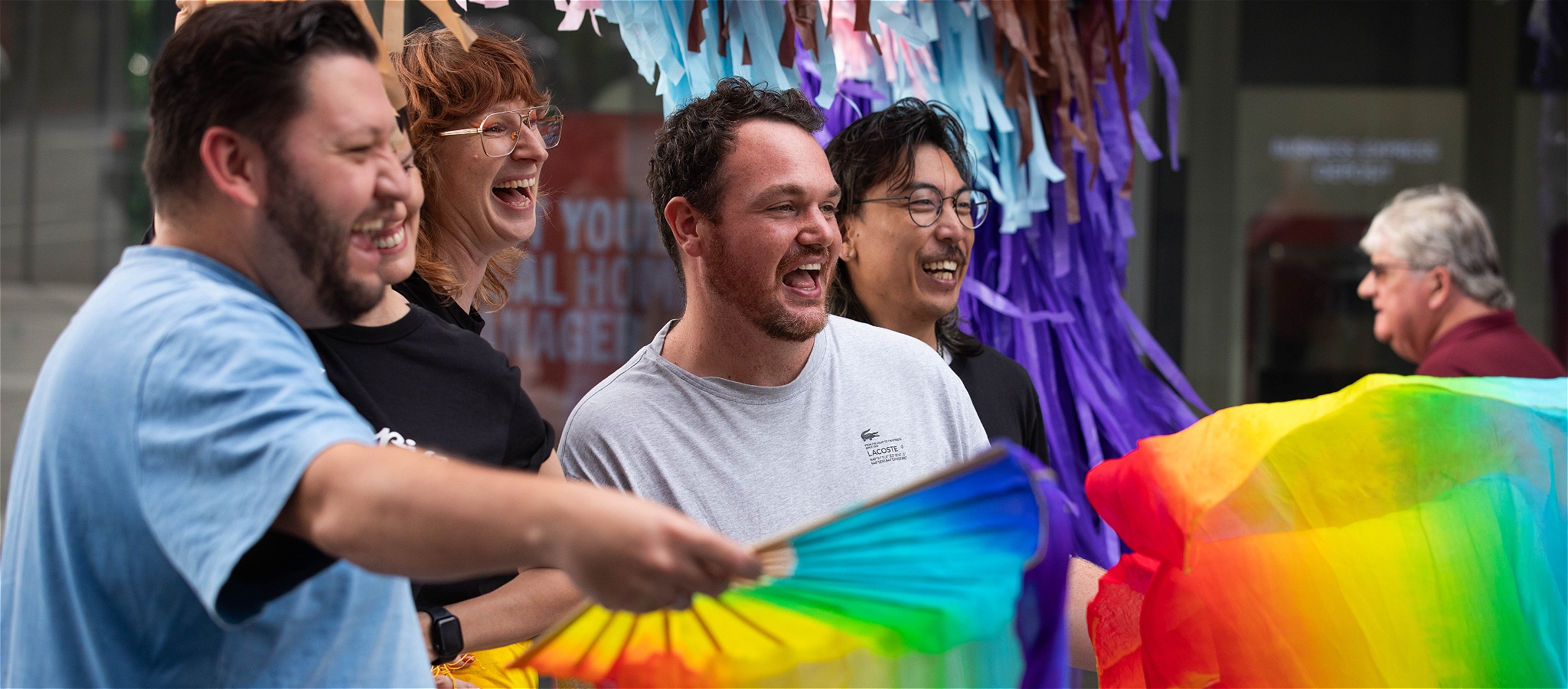 Three drag artists collaged over a beach backdrop, flanked by grass umbrellas and disco balls.