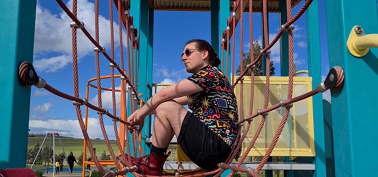 Gabriel sitting amongst some ropes in a playground setting