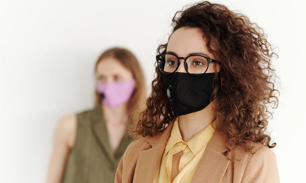 Two young female-identifying people wearing masks