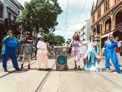 Six people posing around a graffitied rubbish bin on the tram tracks in Gertrude Street, Fitzroy