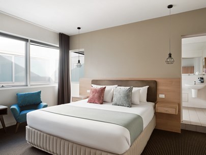 Room in the hotel showing a large bed and a modern ensuite bathroom in the background