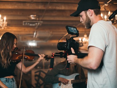 Musicians being photographed while performing in a large room with a chandelier behind them