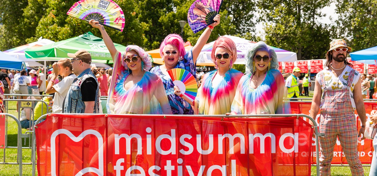 Four colourful people in rainbow clothes and wigs at Carnival 2023