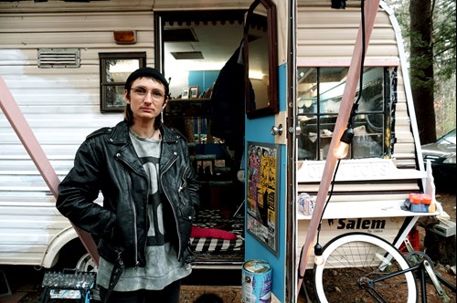 Photo of Tommi standing in front of the open door of a caravan
