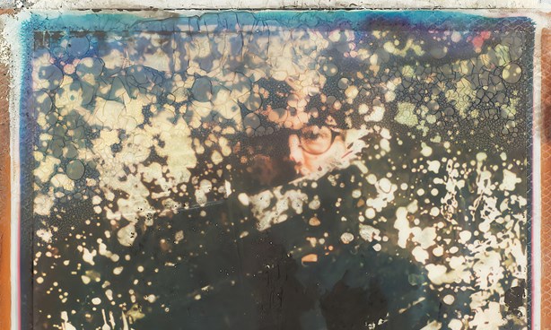 Matthew Schiavello standing behind a speckled window - very hard to make out their features