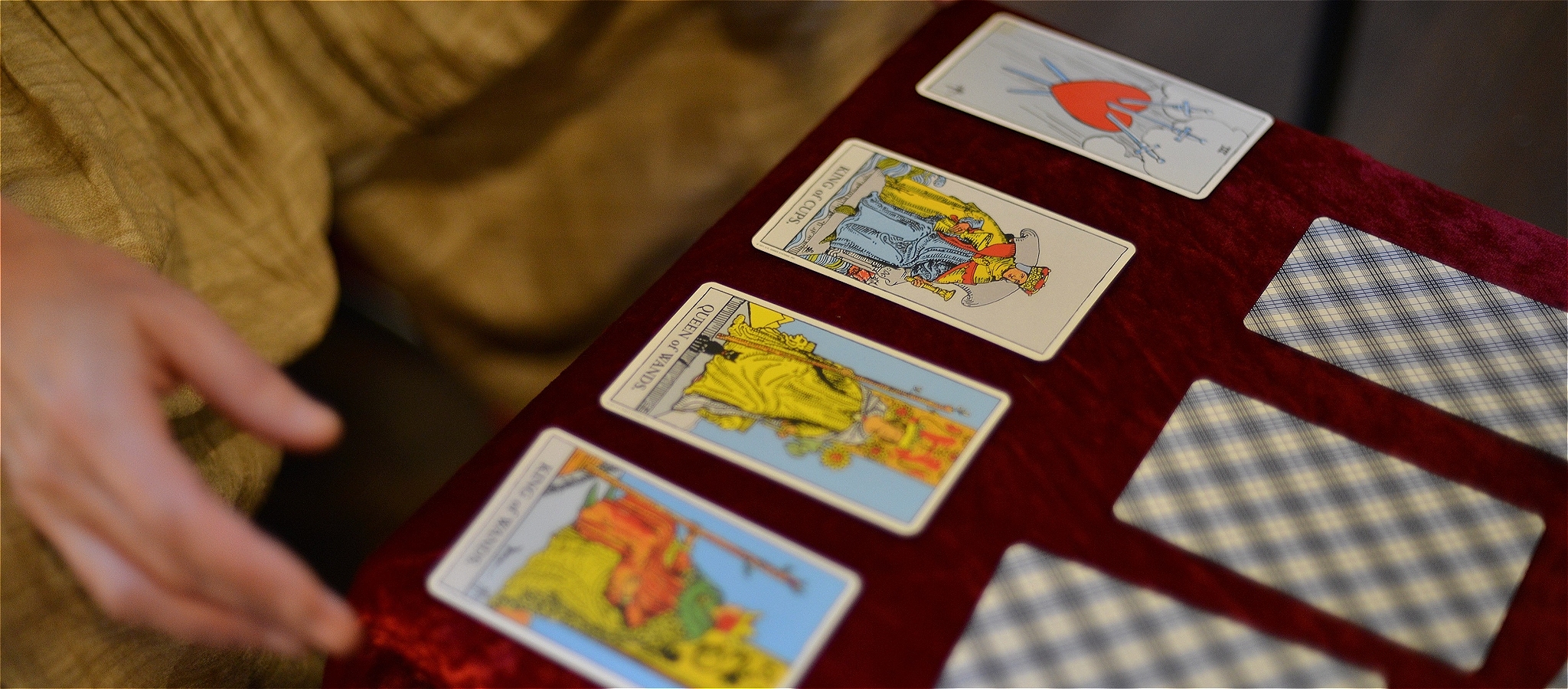 Pianist Danaë Killian lays out tarot cards. Their hands express dismay as they uncover the image of three swords piercing a red heart.