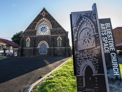 Photo of the outside of the Bluestone Church Arts Space, including their sign in the foreground