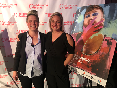 Felicity with wife Sam standing in front of Midsumma artwork