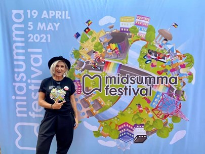 Sasha Catalano standing in front of the 2021 Midsumma Festival hero image