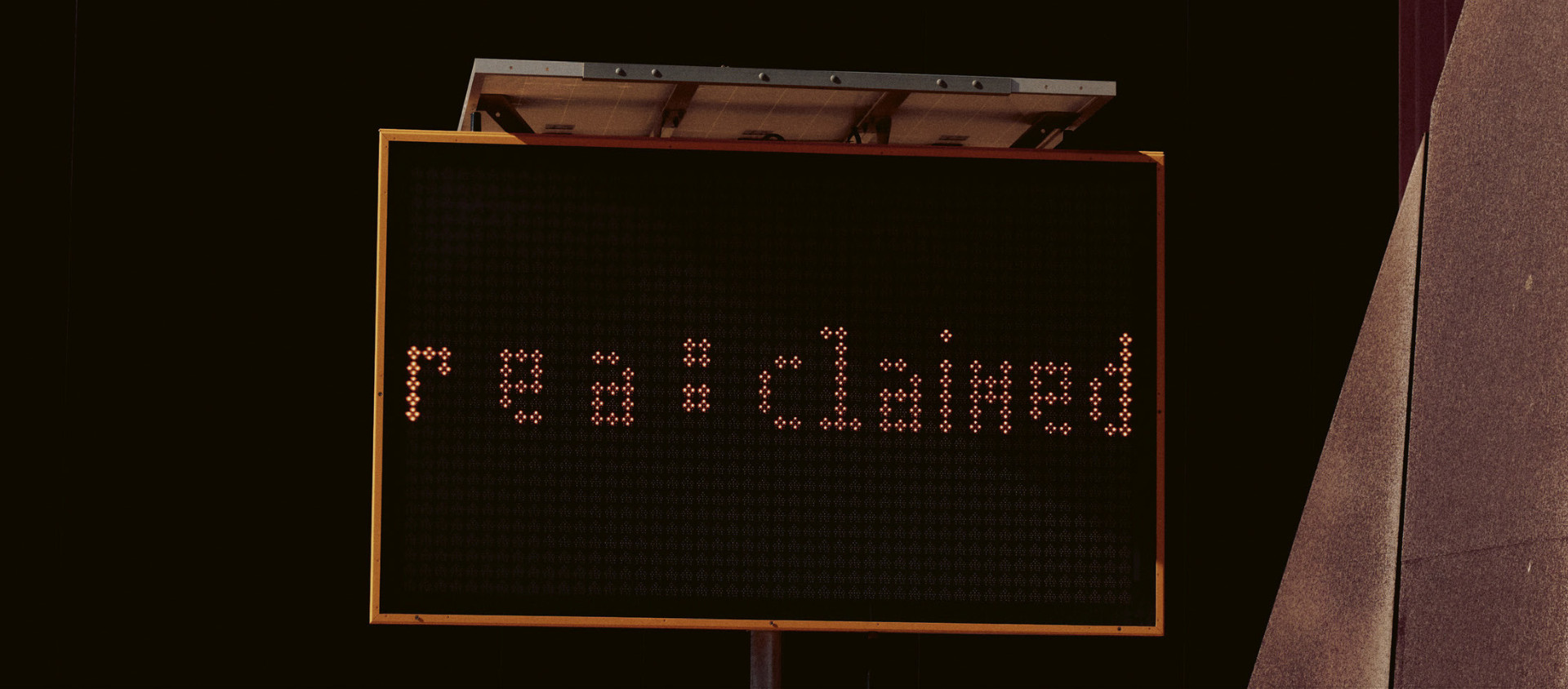 A big light-up road sign containing the title of the exhibition r e a : c l a i m e d