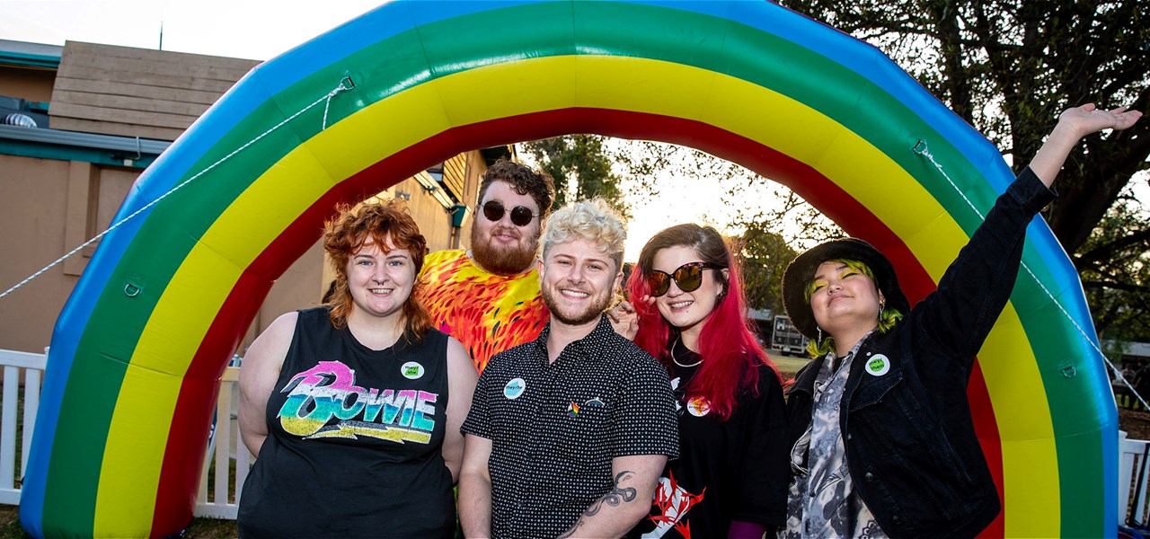 a group of people standing in front of a giant inflatable rainbow